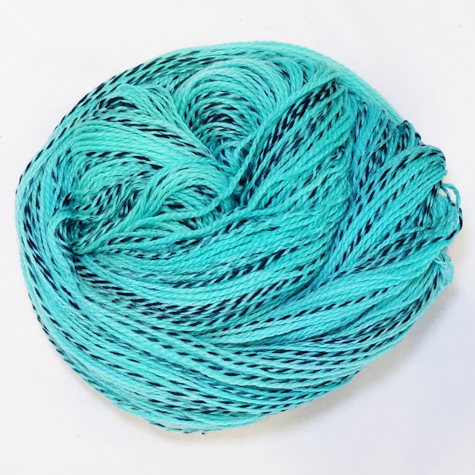 Hand-dyed fingering weight yarn in bright turquoise-teal with aqua and green undertones and black twisted through throughout.