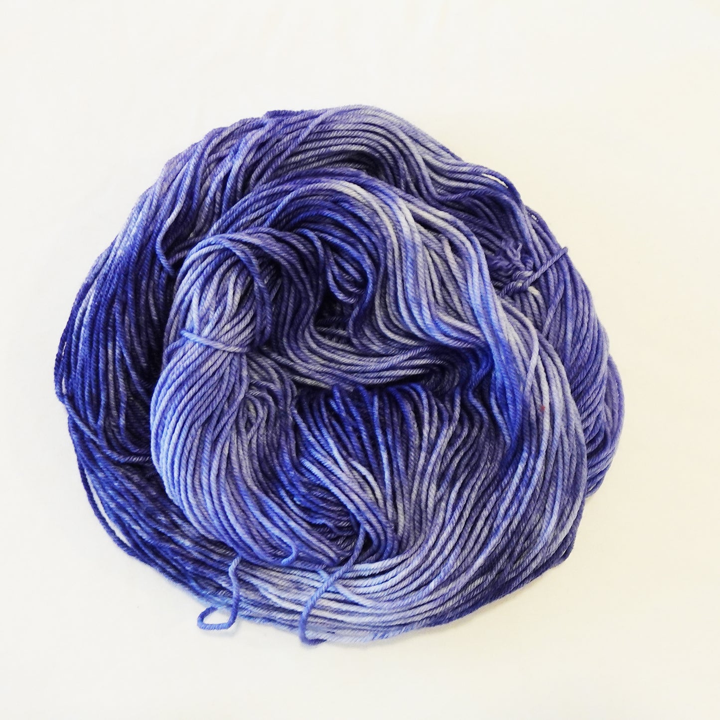 Hand-dyed yarn skein in layered blue tones with variegated depth ranging from light to deep shades