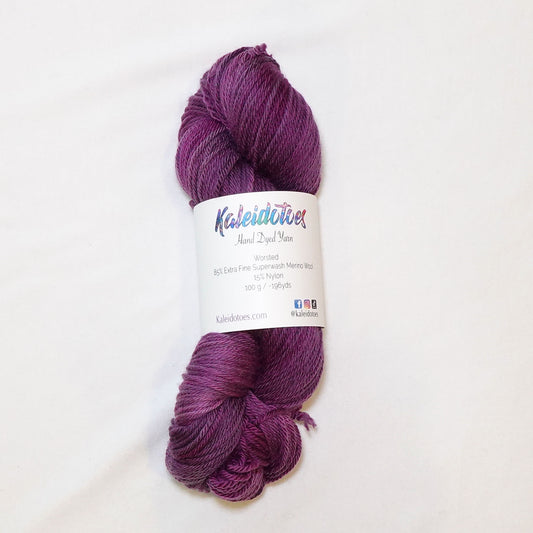 Hand-dyed worsted weight yarn in deep plum and eggplant tones with subtle magenta variation throughout.