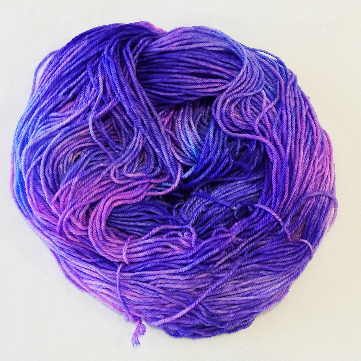 Hand-dyed yarn skein with layered pink and purple tones blended smoothly with soft tonal transitions