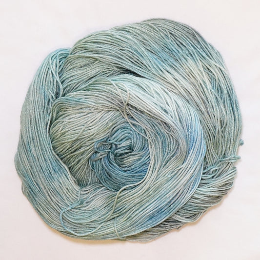Hand-dyed fingering weight yarn in soft blue-green, dusty sage, pale aqua, and silvery gray tones.