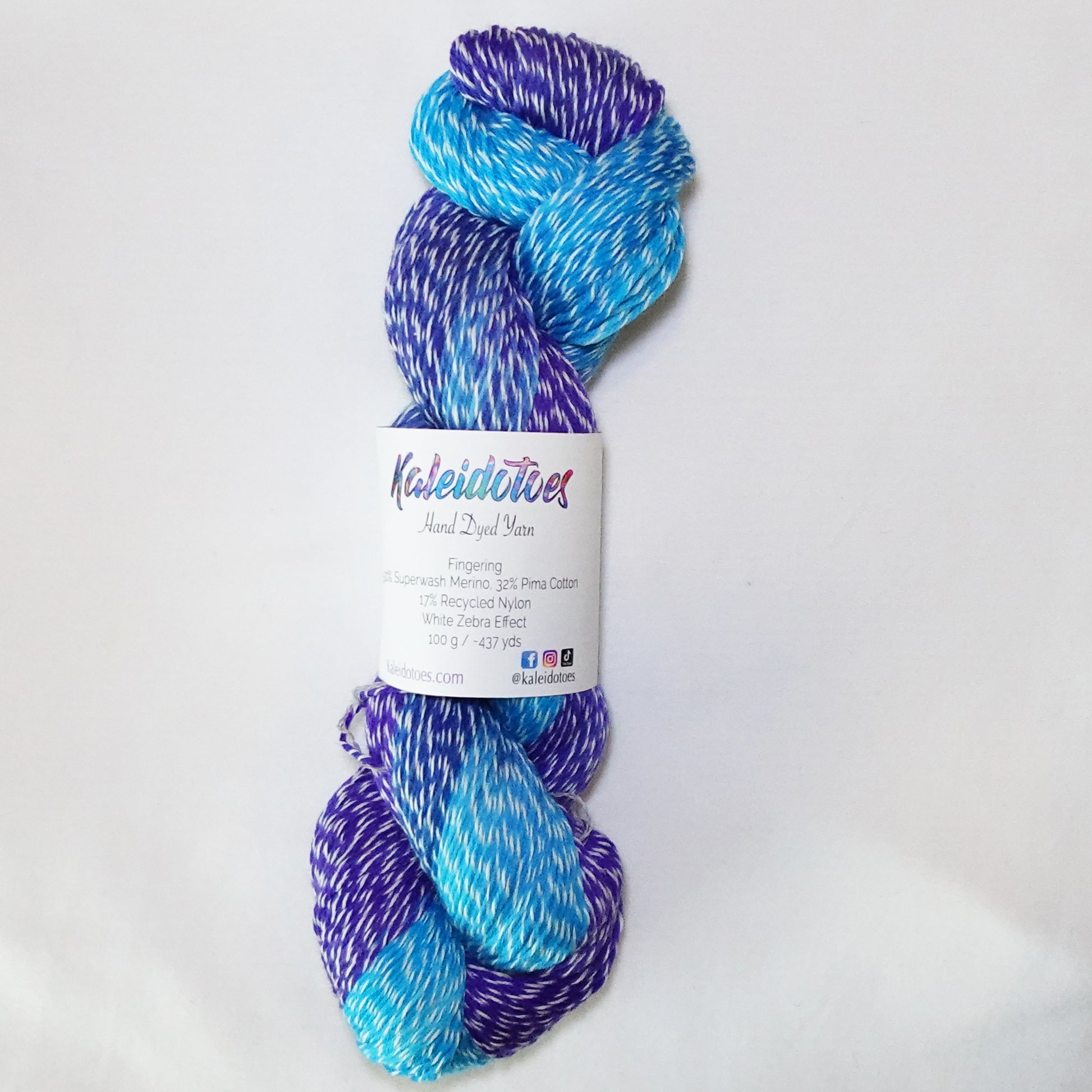 Hand-dyed white zebra base fingering weight yarn in bright turquoise, deep blue, and violet purple with white plied throughout.