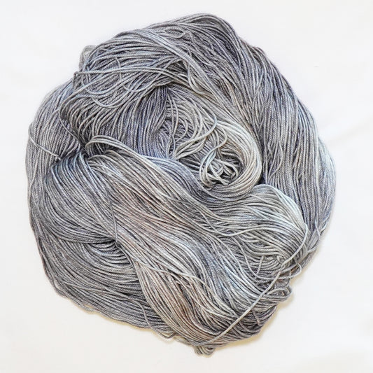 Hand-dyed fingering weight yarn in weathered stone gray, pale blue-gray, soft taupe, and dusty fawn tones.