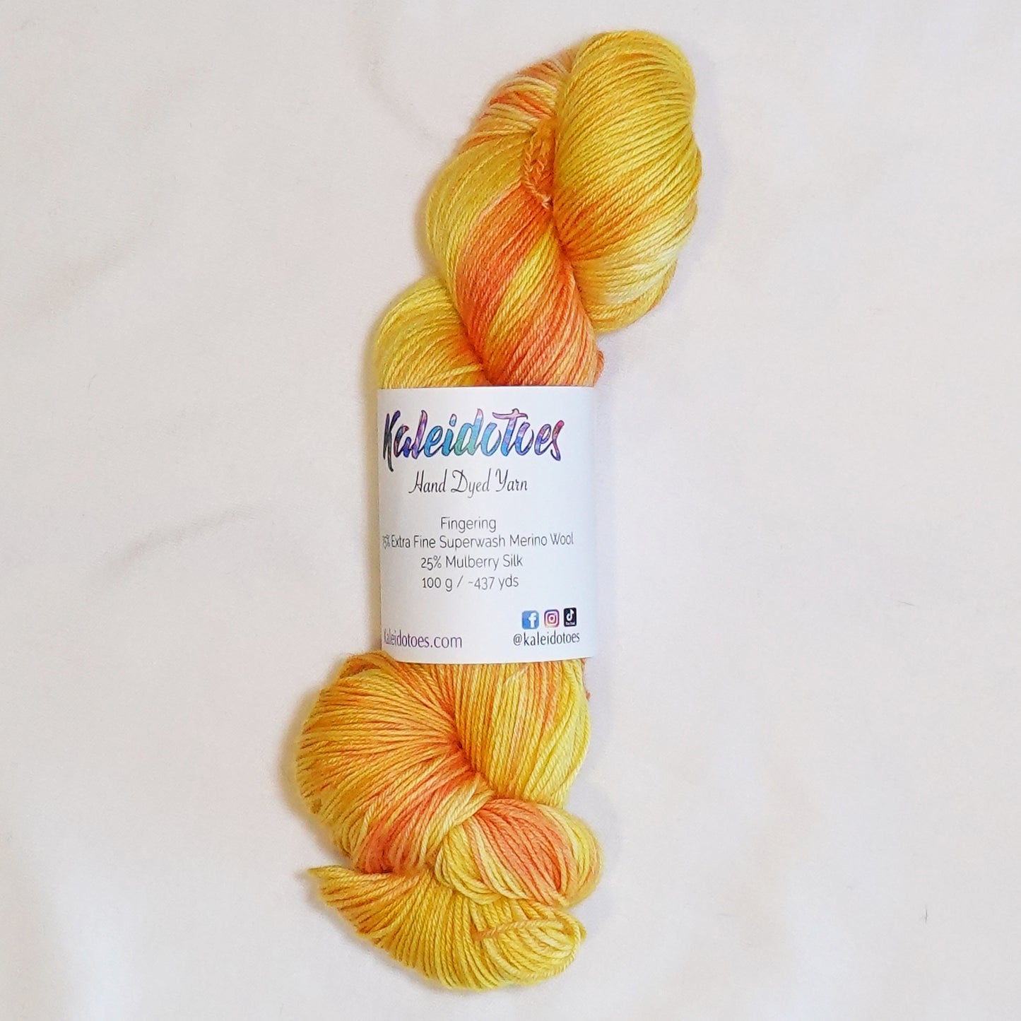 Hand-dyed fingering weight yarn in golden yellow, warm apricot, buttery yellow, and soft orange tones.