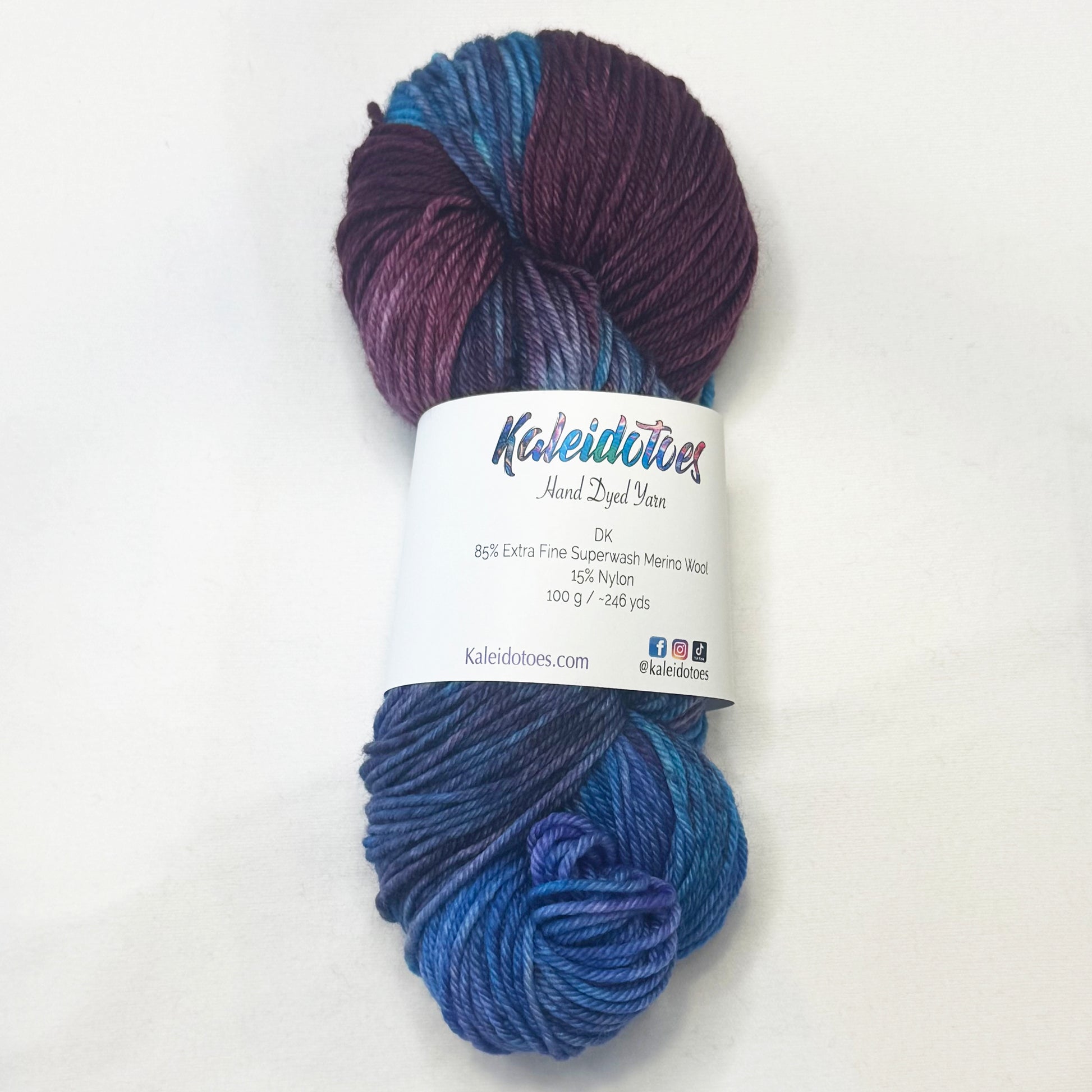 Hand-dyed yarn in shades of cranberry, turquoise, indigo, and soft white — luminous and richly blended with a cosmic glow.