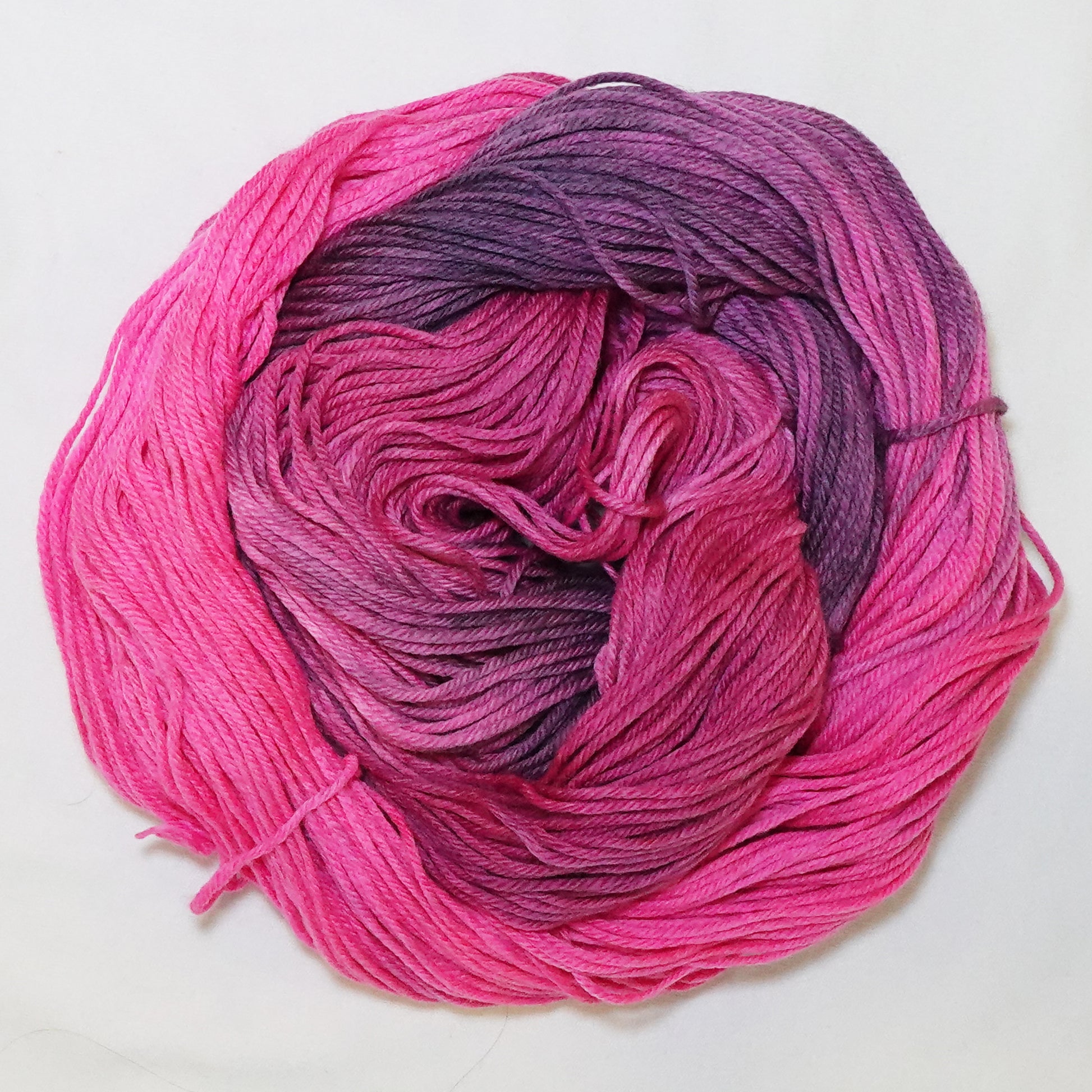 Hand-dyed DK weight yarn in hot pink, deep mauve, and dusty amethyst - vivid, moody, and richly variegated throughout.