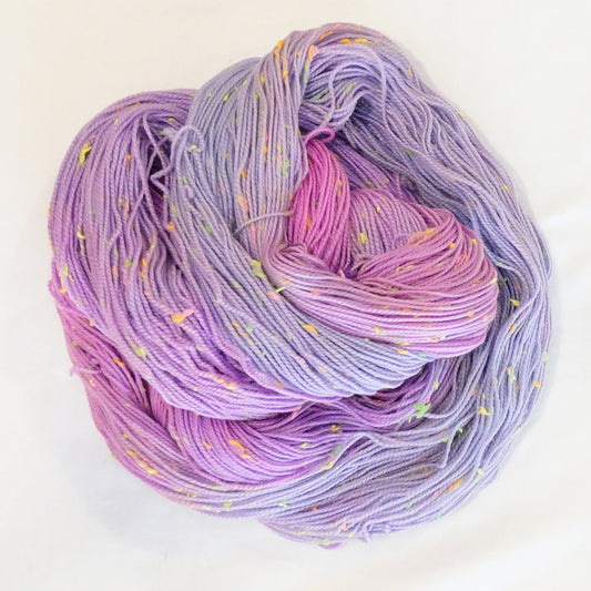 Hand-dyed yarn in soft lavender, lilac, and light pink tones with bright neon flecks — dreamy, airy, and softly blended.