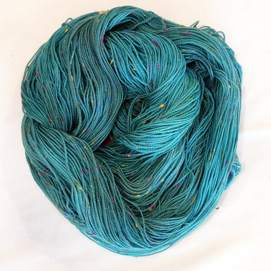 Hand-dyed yarn in layered teal and aqua tones with colorful flecks — vibrant, fresh, and reminiscent of dragonfly wings in motion.