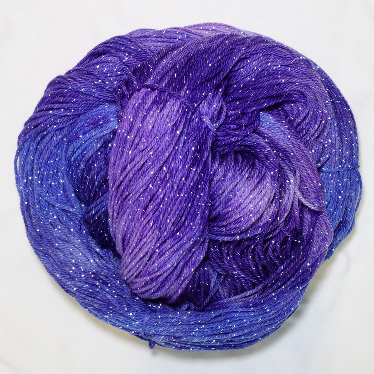 Hand-dyed silver metallic fingering weight yarn in deep violet, lilac, and dark periwinkle with silver sparkle.