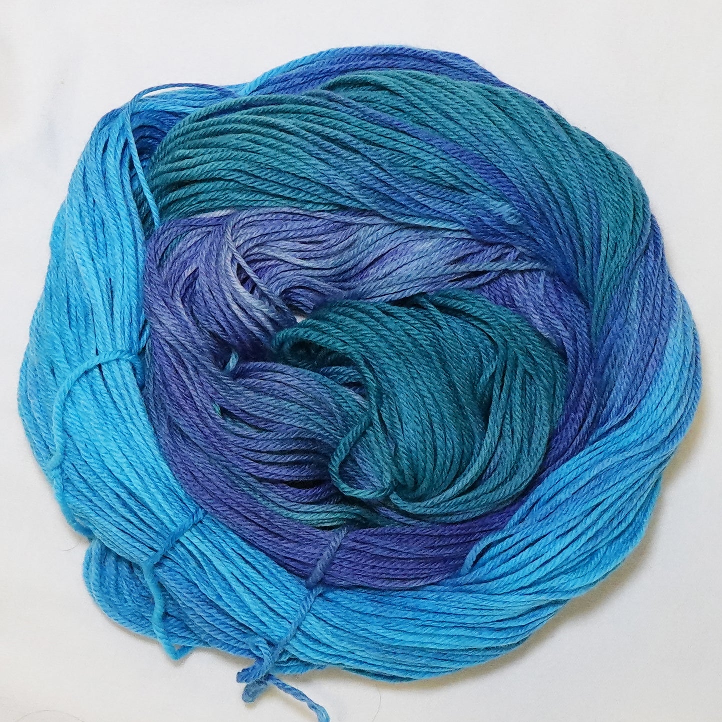 Hand-dyed DK weight yarn in bright turquoise, teal-green, blue-purple, and blue-grey - variegated and deeply saturated throughout.