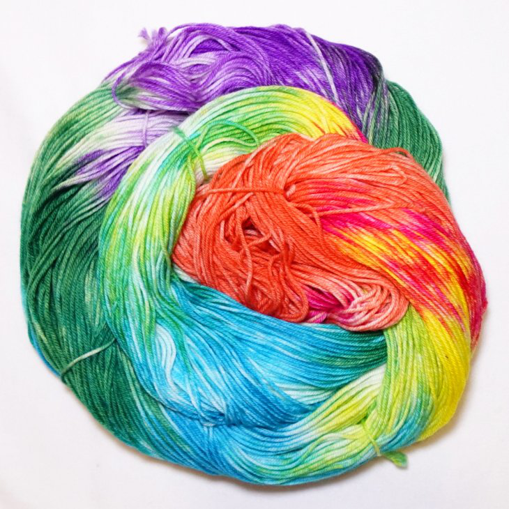 Flaunt Your Feathers hand-dyed fingering weight yarn showing vivid purple, green, turquoise, yellow, pink, and orange color placement.