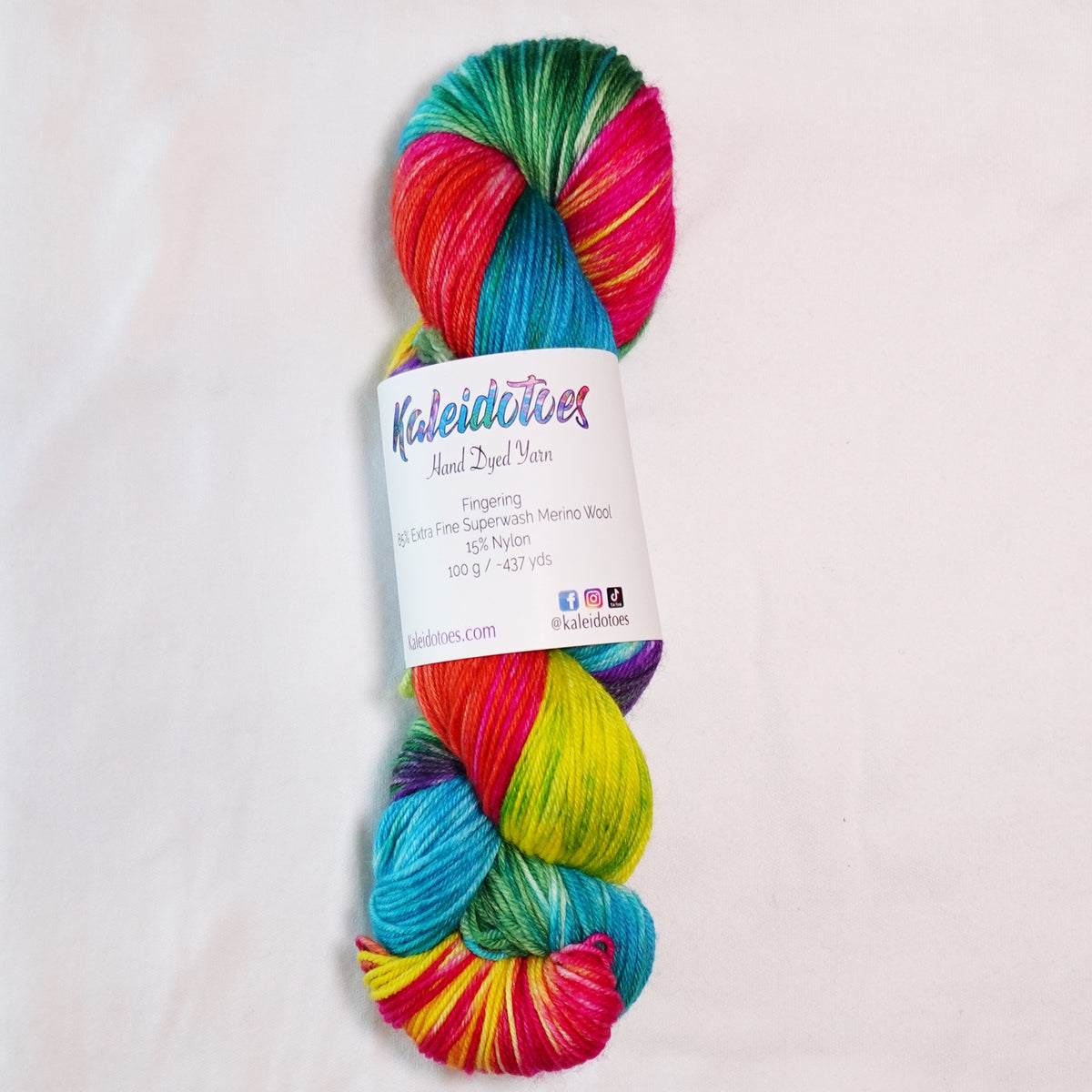 Hand-dyed fingering weight yarn with hot pink, turquoise blue, vivid yellow, green, orange, and purple in a bright multicolor variegated colorway.