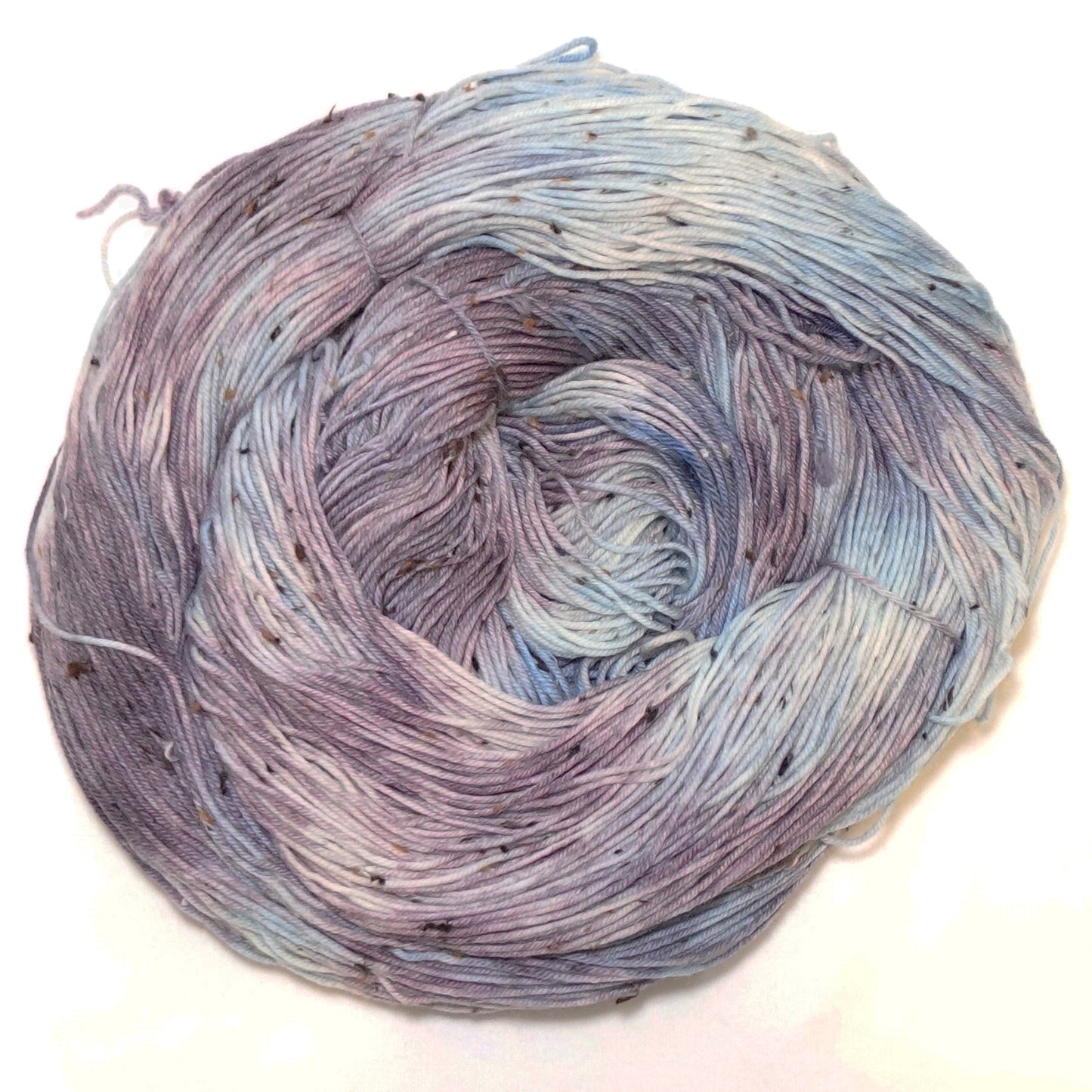 Hand-dyed tweed yarn in dusty mauve and soft grey-blue — muted, atmospheric, and quietly complex with subtle flecks throughout.