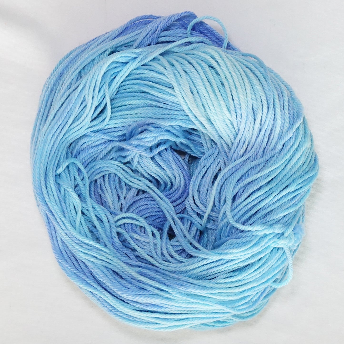 Hand-dyed worsted weight yarn in soft sky blue and periwinkle with light ice blue tones throughout.