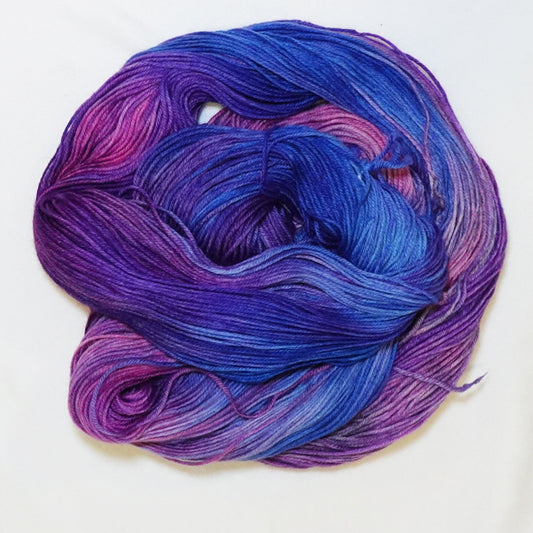 Hand-dyed fingering weight yarn in royal purple, sapphire blue, orchid pink, and magenta with saturated jewel-tone color transitions.