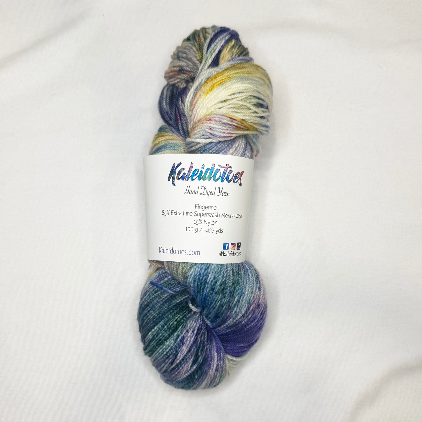 Hand-dyed yarn in soft blues, green, and pink and yellow speckles — light, floral, and garden-inspired.