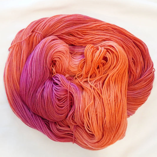 Hand-dyed yarn in blazing orange, coral, and red-orange tones with a flash of dark magenta — wide, warm, and intensely radiant.