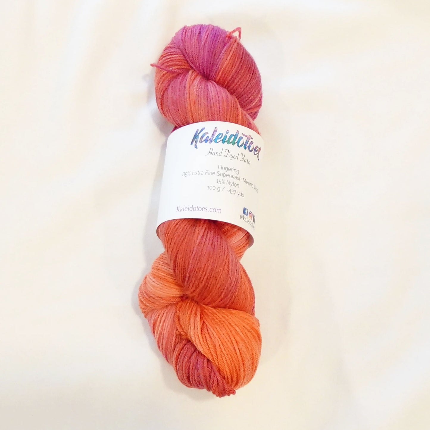 Hand-dyed yarn in blazing orange, coral, and red-orange tones with a flash of dark magenta — wide, warm, and intensely radiant.
