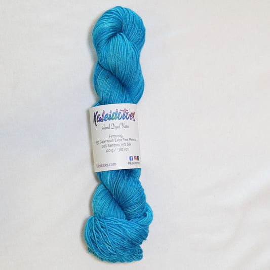 Hand-dyed fingering weight yarn in tonal turquoise blue with luminous shifts throughout.