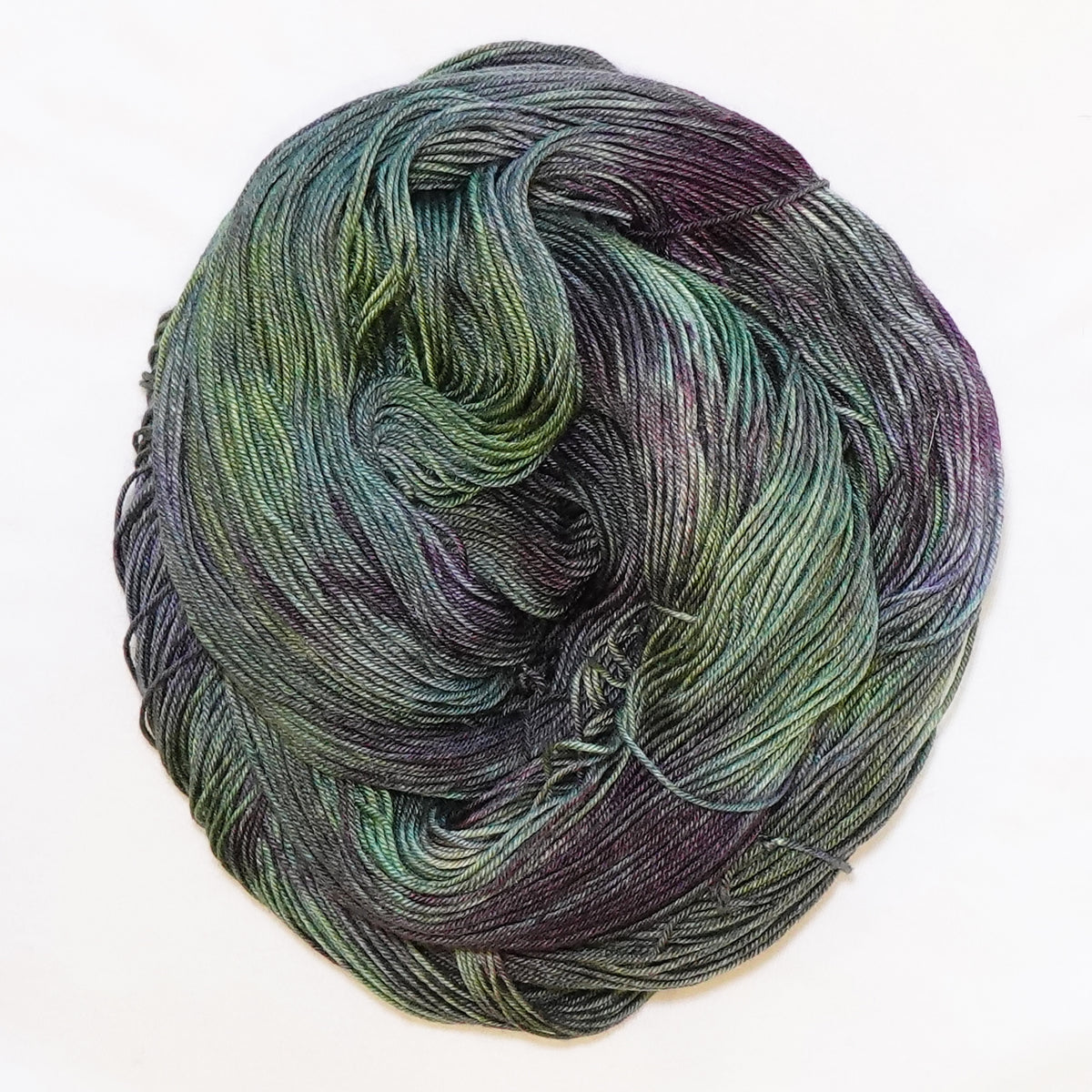 Hand-dyed fingering weight yarn in cactus green, blue-green, olive, and deep aubergine tones.