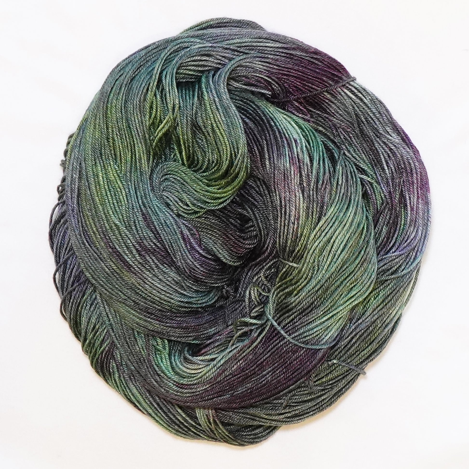 Hand-dyed fingering weight yarn in cactus green, blue-green, olive, and deep aubergine tones.