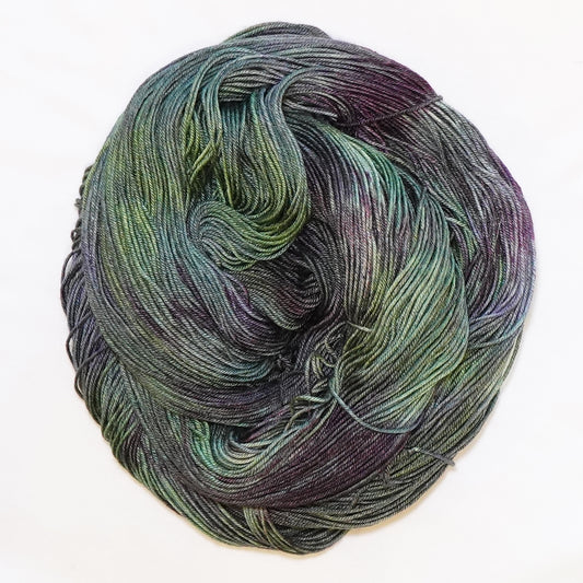 Hand-dyed fingering weight yarn in cactus green, blue-green, olive, and deep aubergine tones.
