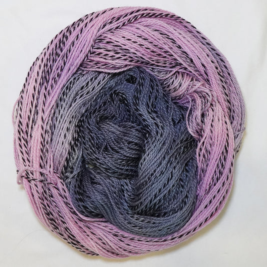 Hand-dyed fingering weight yarn in dusty pink, mauve, and deep blue-grey with black twisted through throughout.