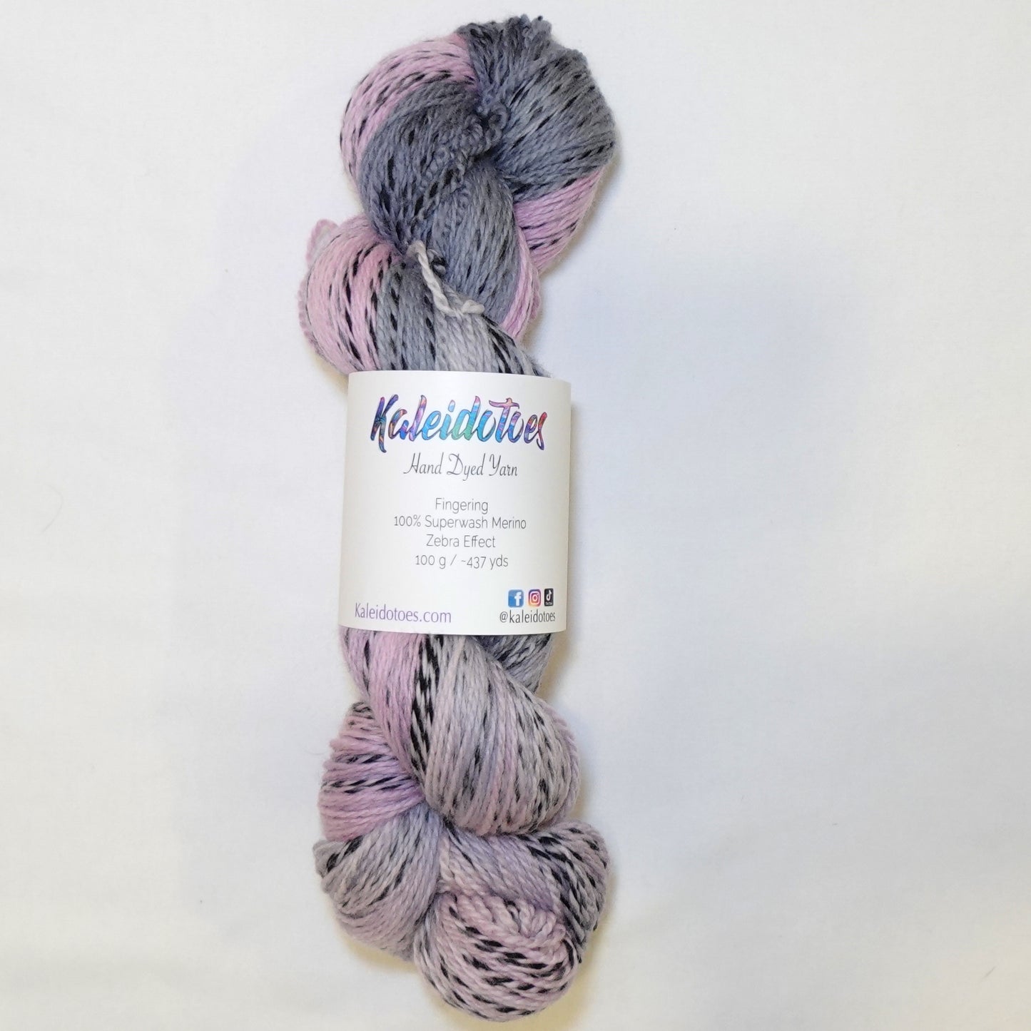 Hand-dyed fingering weight yarn in dusty pink, mauve, and deep blue-grey with black twisted through throughout.