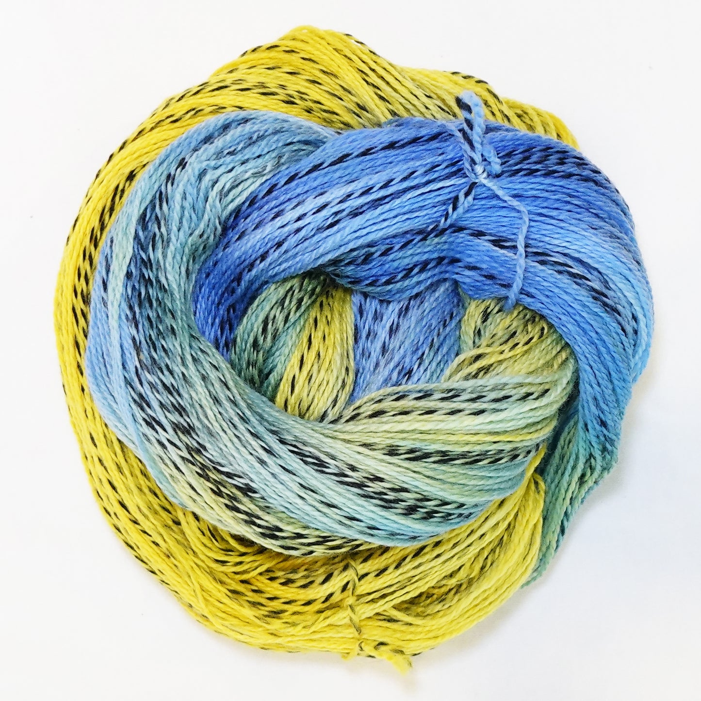 Hand-dyed fingering weight yarn in sunflower yellow and cornflower blue with black twisted through and a soft sage-green where the colors meet.