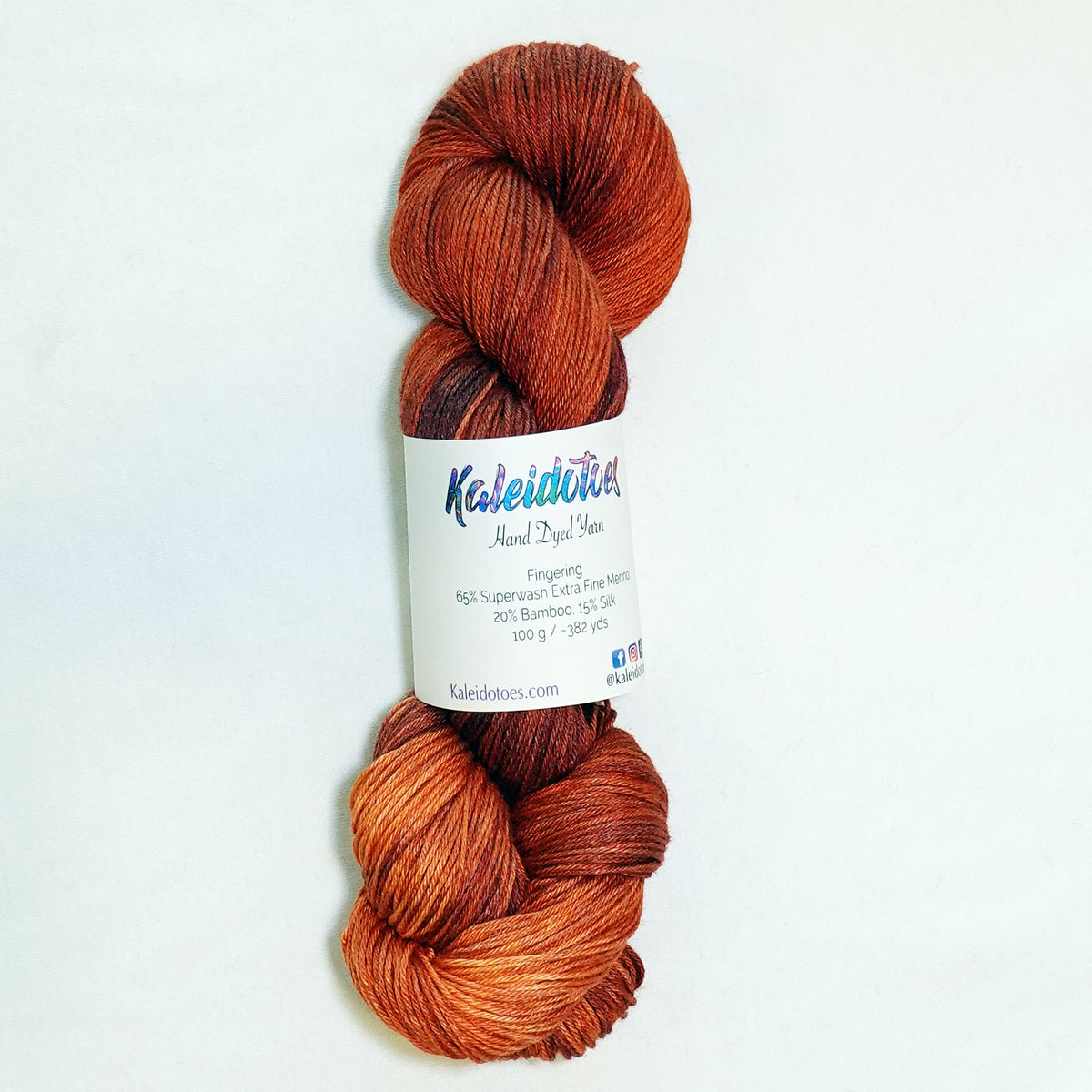 Hand-dyed fingering weight yarn in warm reddish-brown with coppery highlights and deep rust tones.