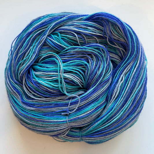 Indie dyed yarn skein, Midnight Current Stripe, variegated deep blue, grey, and teal.