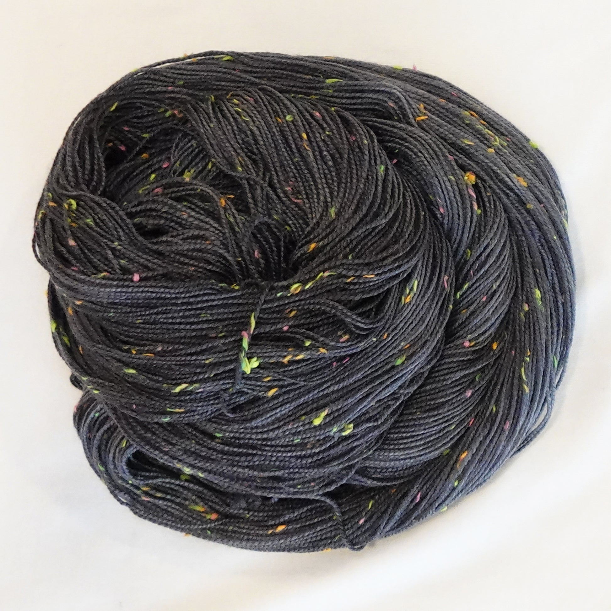 Hand-dyed yarn in deep charcoal with bright flecks of lime, pink, and orange — moody with a disco-inspired pop of color.