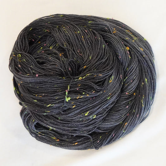 Hand-dyed yarn in deep charcoal with bright flecks of lime, pink, and orange — moody with a disco-inspired pop of color.