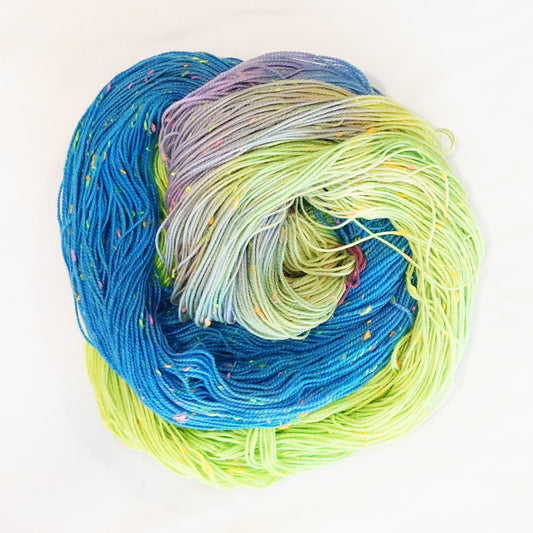 Hand-dyed yarn in bright blue, neon lime, and lavender tones with colorful neon flecks — vibrant, playful, and full of confetti-like energy.