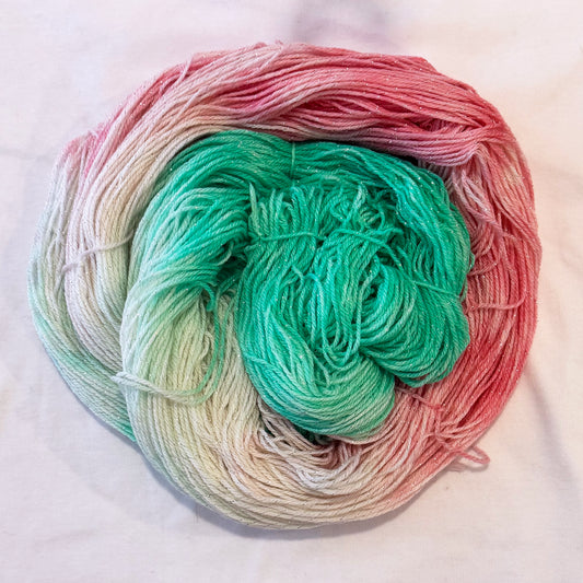 Hand-dyed yarn in mint green, soft pinks, and ivory tones with subtle silver metallic throughout.