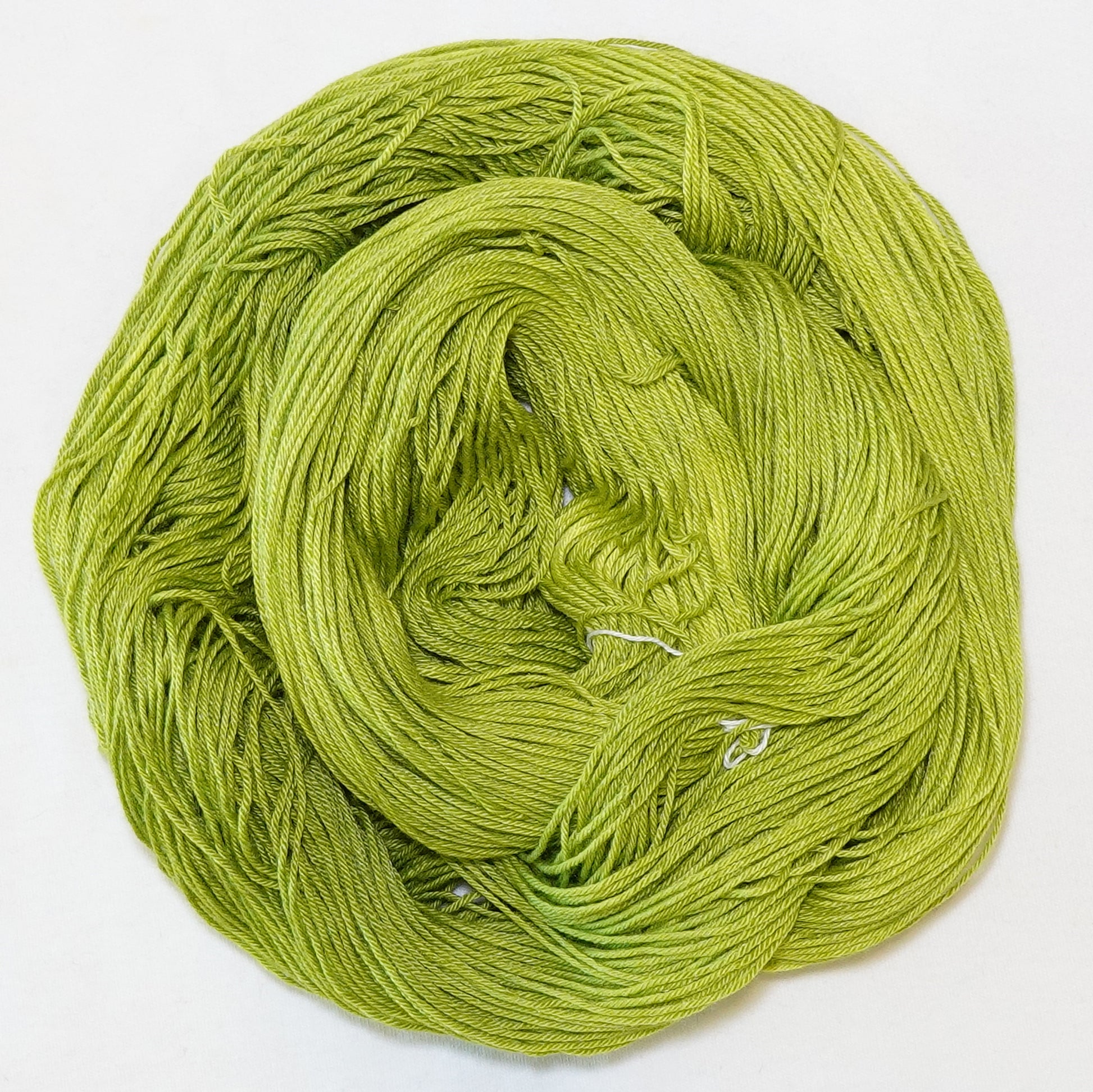 Hand-dyed fingering weight yarn in tonal electric chartreuse green.