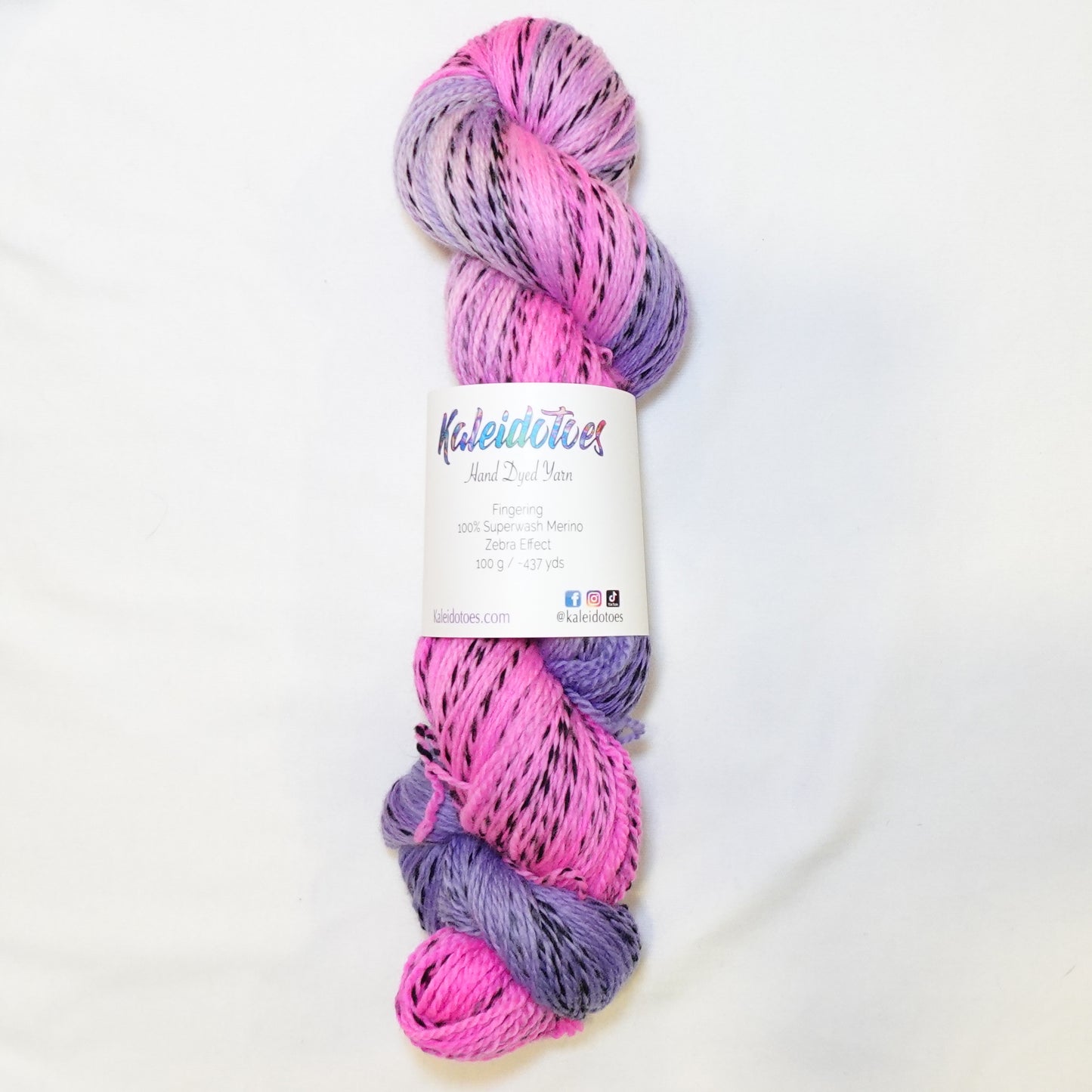 Hand-dyed fingering weight yarn in hot pink and soft lilac with black twisted through and a muted orchid blend where the colors meet.