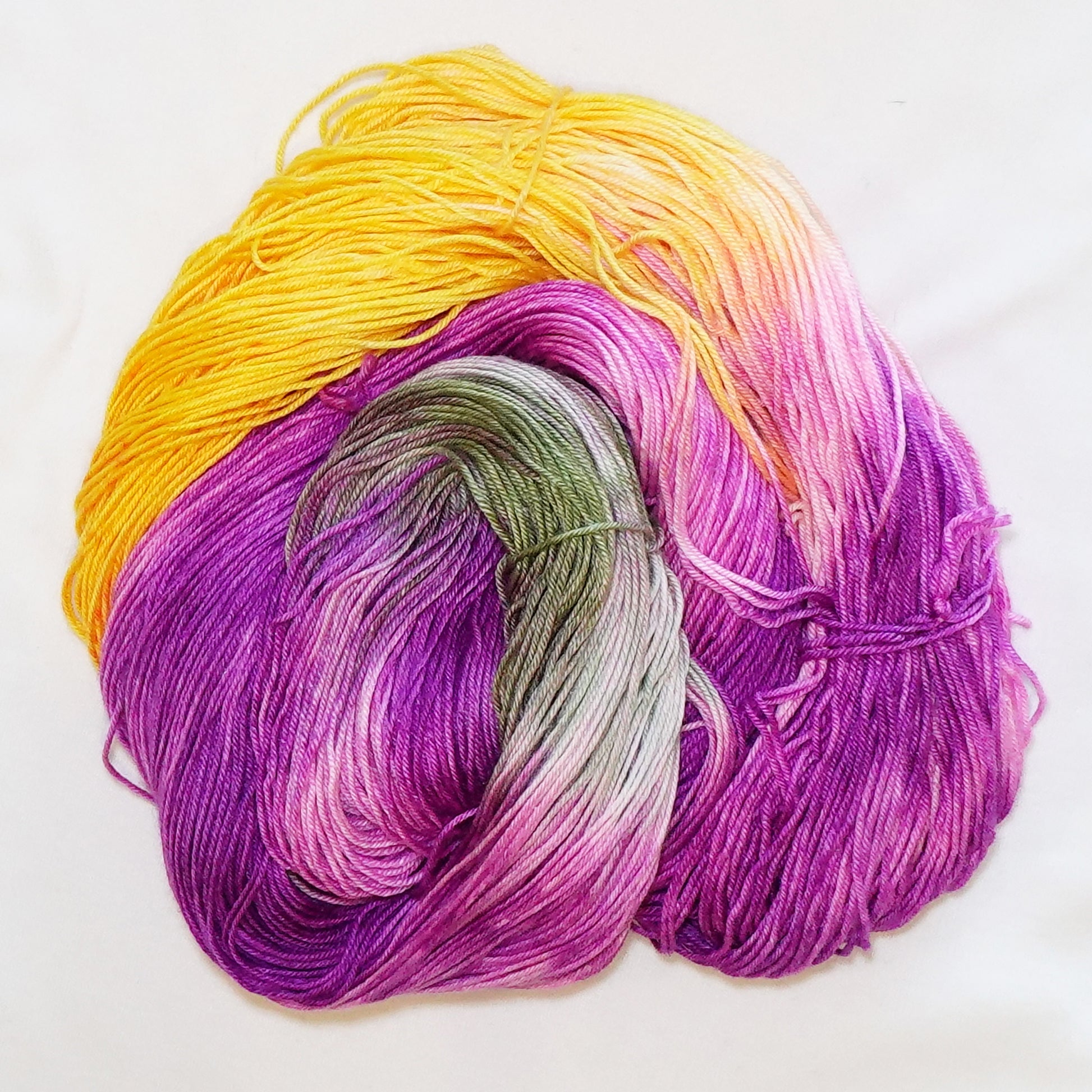 Hand-dyed fingering weight yarn in saturated purple, magenta, hot pink, golden yellow, and muted cactus green.