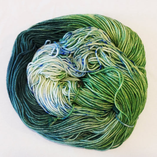 Hand-dyed yarn skein in layered teal and green tones with subtle teal and green speckles