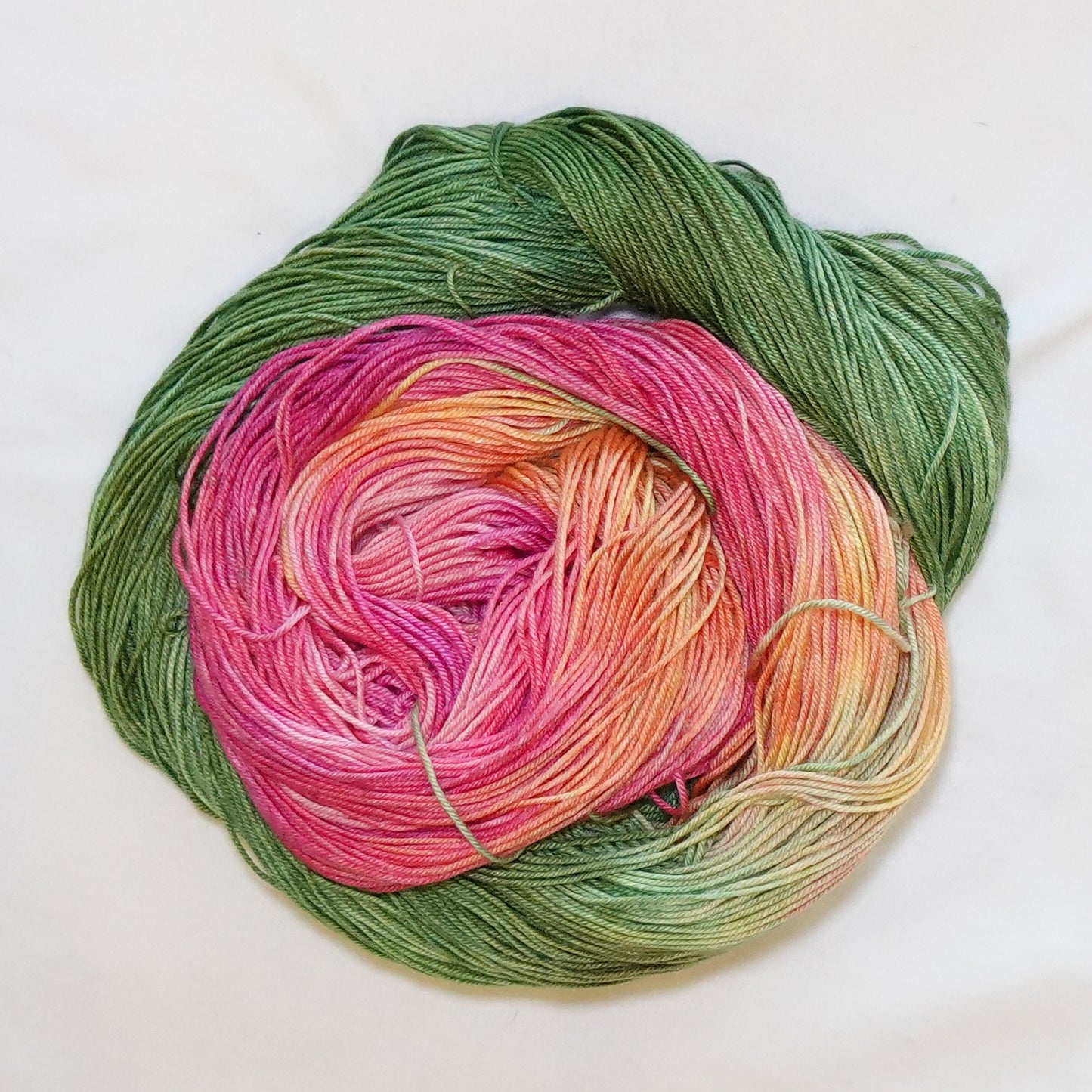 Hand-dyed fingering weight yarn in cactus green, vivid pink-red, coral, peach, and warm yellow tones.