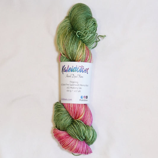 Hand-dyed fingering weight yarn in cactus green, vivid pink-red, coral, peach, and warm yellow tones.