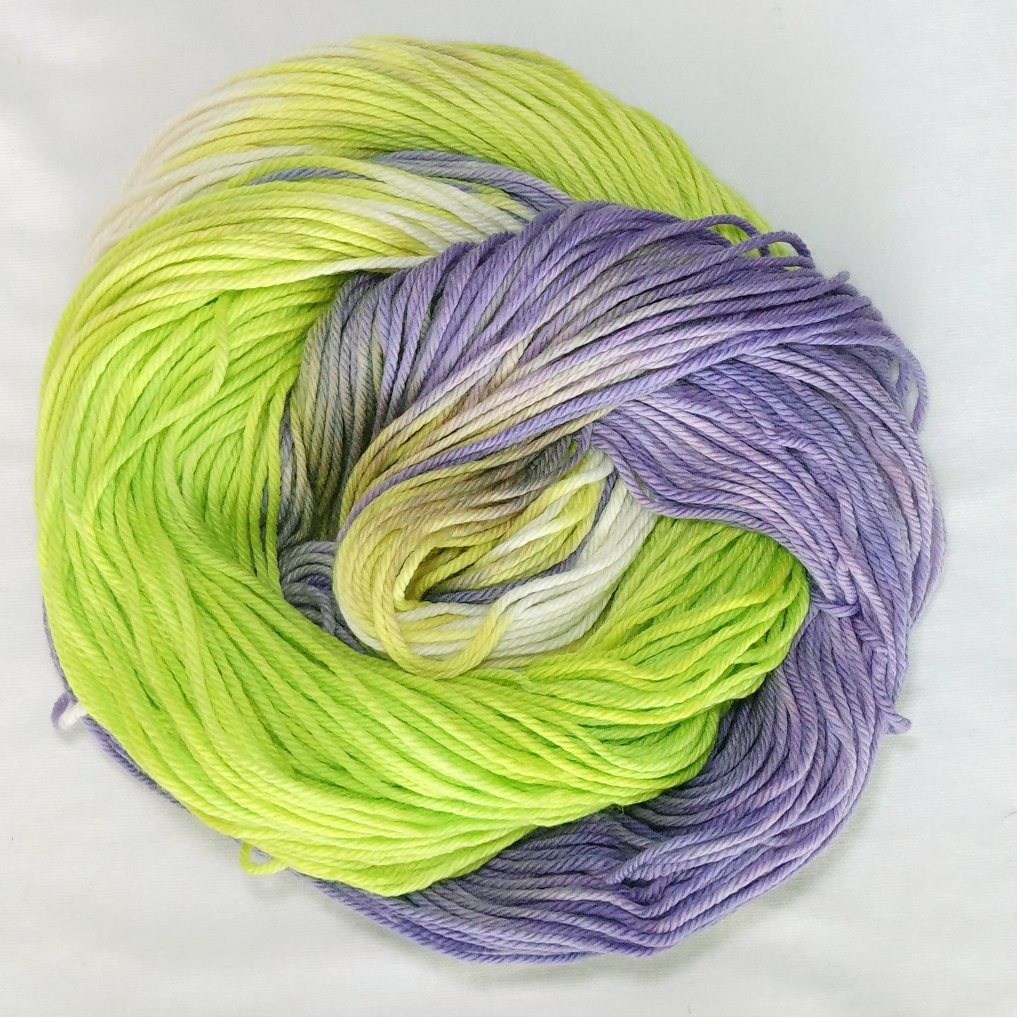 Hand-dyed worsted weight yarn in electric chartreuse, lime green, creamy white, lilac, and wisteria.
