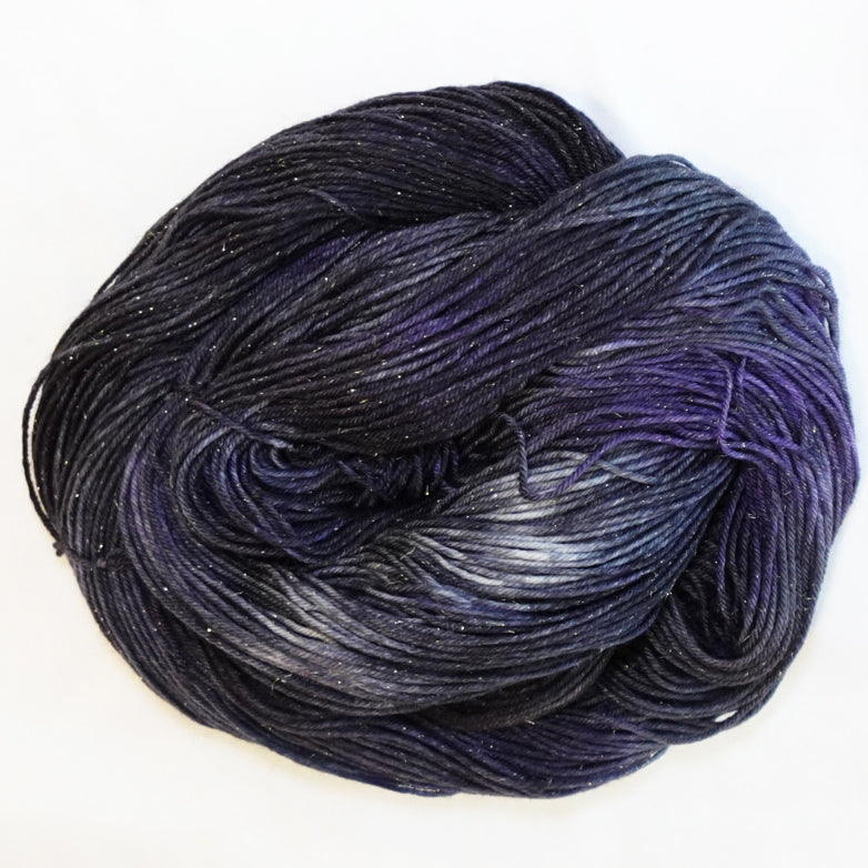 Hand-dyed gold metallic fingering weight yarn in near-black, smoky charcoal and deep violet with a fine gold metallic thread.