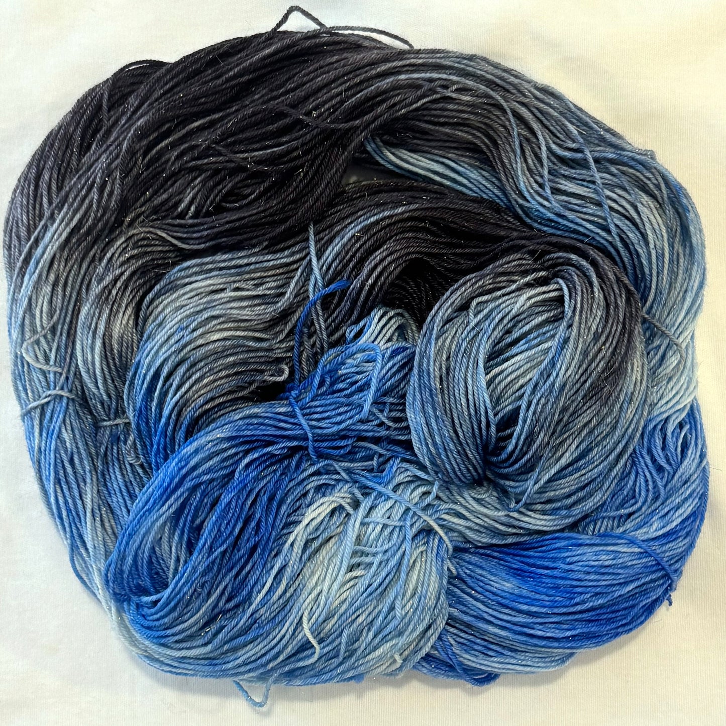 Hand-dyed yarn in charcoal, slate, and layered winter blue tones with subtle gold threads throughout.