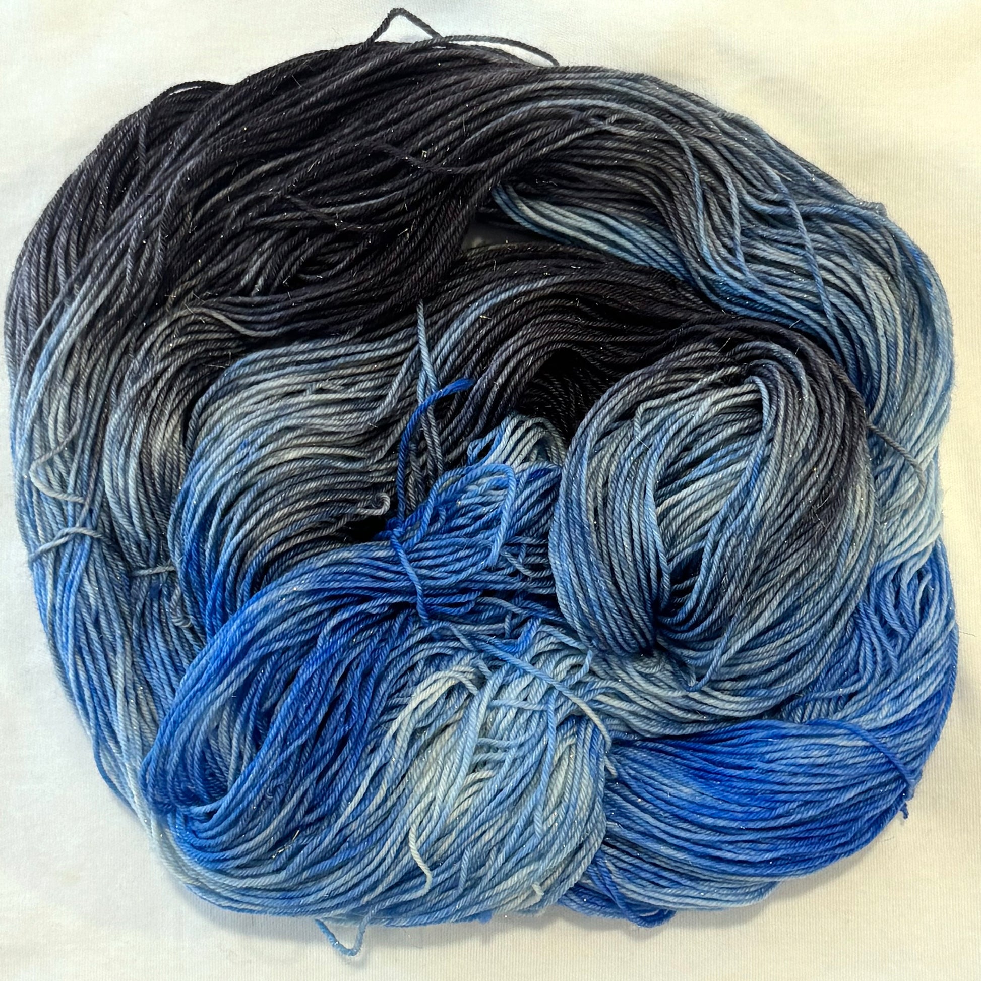 Hand-dyed yarn in charcoal, slate, and layered winter blue tones with subtle gold threads throughout.