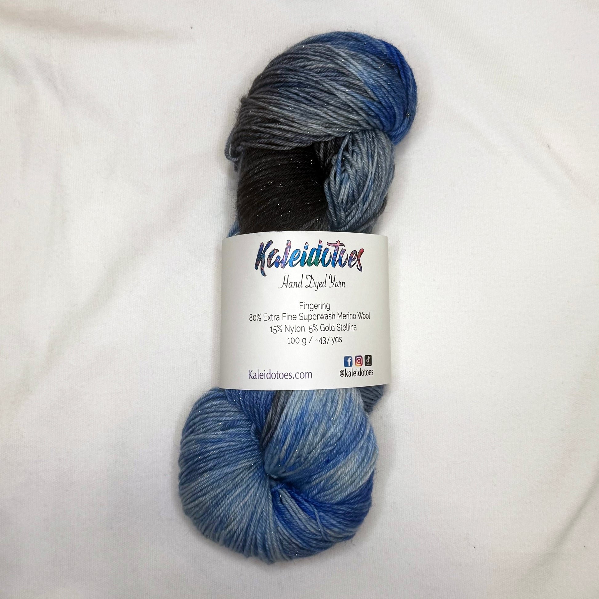 Hand-dyed yarn in charcoal, slate, and layered winter blue tones with subtle gold threads throughout.