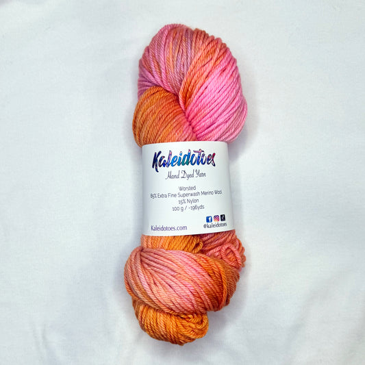 Hand-dyed yarn in shades of peach, golden amber, and blush pink — glowing softly like a sunset sky.