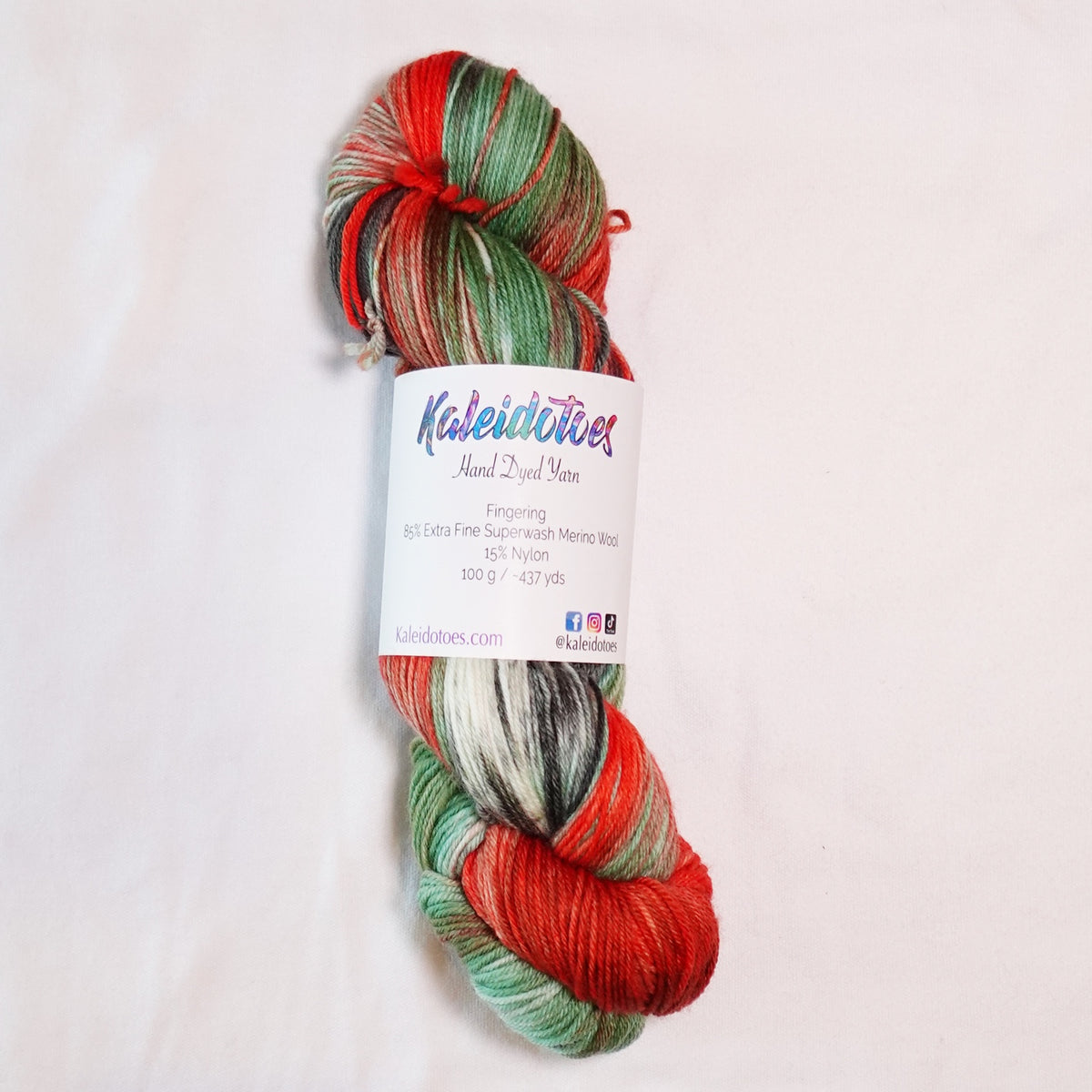 Hand-dyed fingering weight yarn with salmon orange, wasabi green, deep black-green nori, and white in a bold variegated colorway.