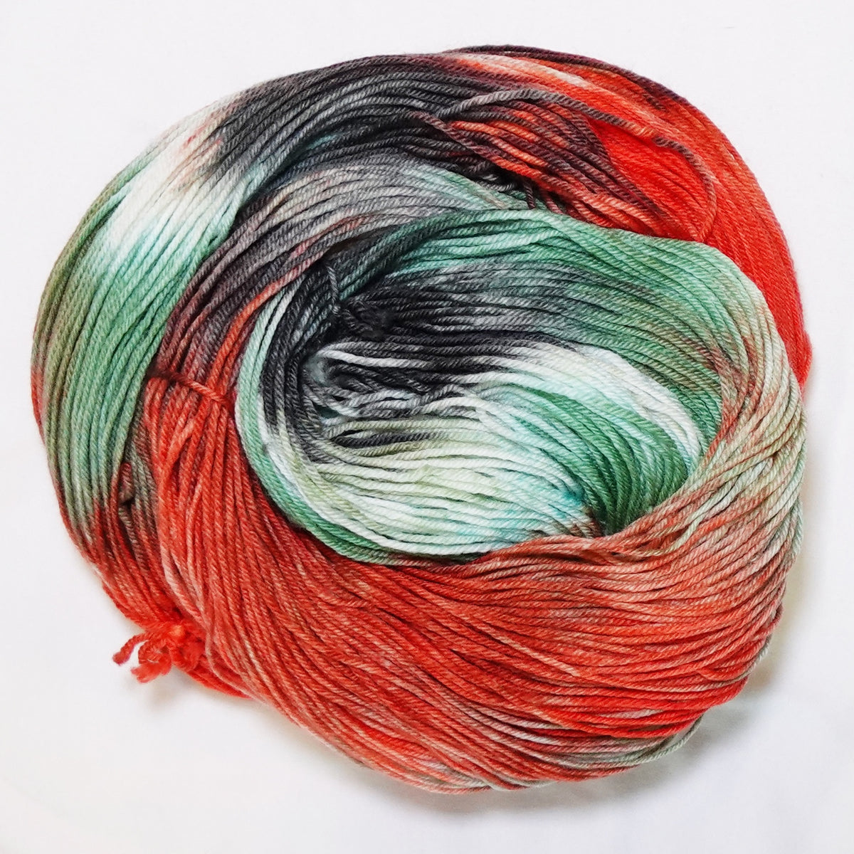 Hand-dyed fingering weight yarn with salmon orange, wasabi green, deep black-green nori, and white in a bold variegated colorway.