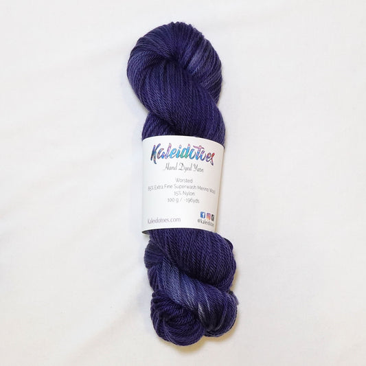 Hand-dyed worsted weight yarn in deep washed indigo blue-violet tones with soft, diffused tonal variation and near-white patches throughout.